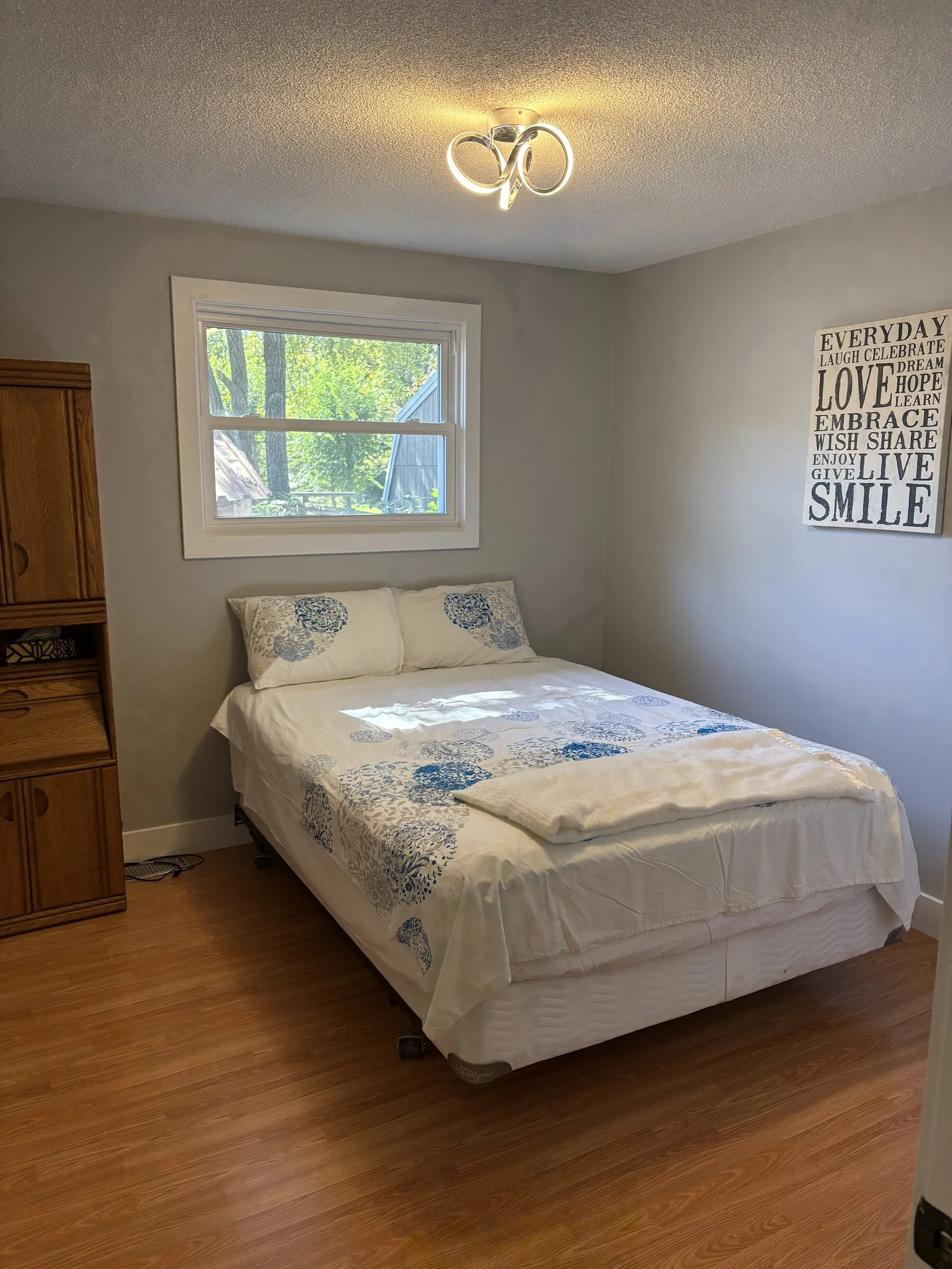 Bedroom with blue floral bedding and a window onto the trees