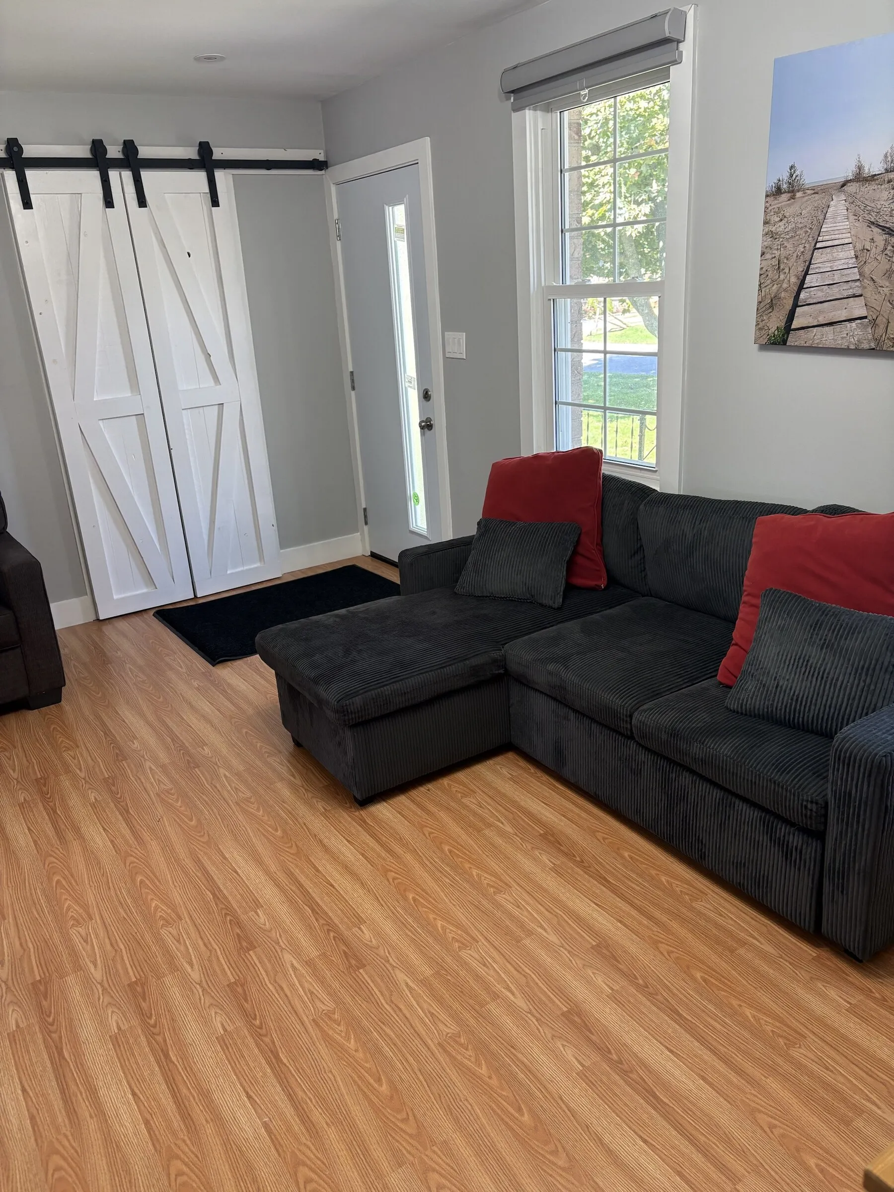 Living room with charcoal sectional, red cushions and barn doors